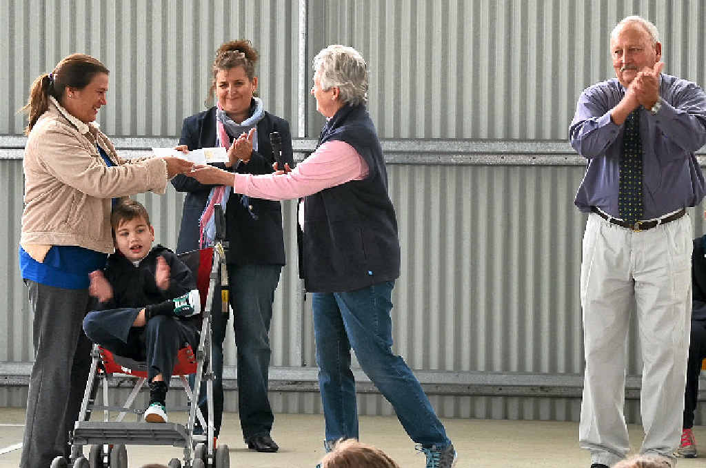 DONATION: Warwick East State School P&C; treasurer Madonna Dwan (back) and principal Warren Elder (right) watch on as P&C; president Cheri O’Neill presents a cheque to Angus Bowles’ mother (left), Sonya.